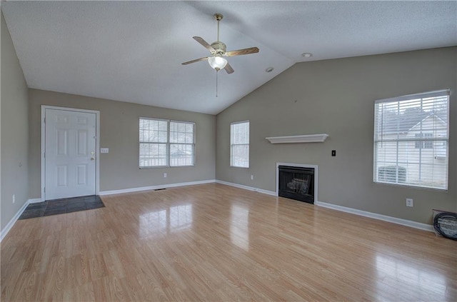 unfurnished living room with ceiling fan, lofted ceiling, a textured ceiling, and light wood-type flooring