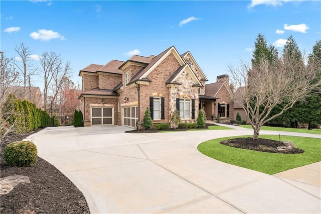 view of front of property featuring brick siding, curved driveway, and a front lawn