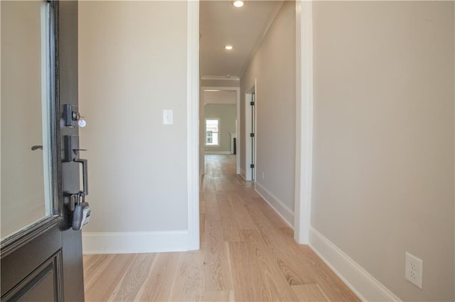 corridor with light wood-type flooring and crown molding