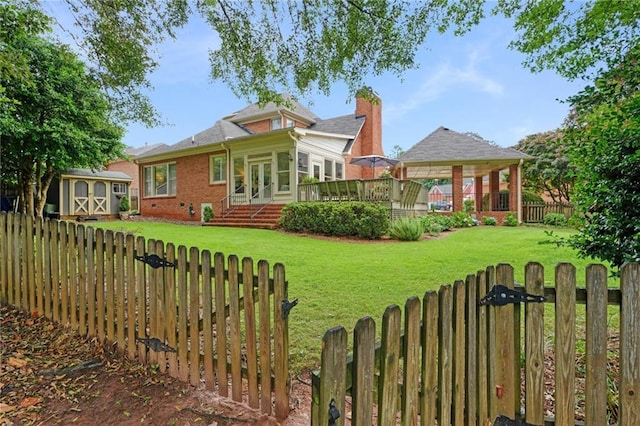 view of yard featuring an outbuilding, a wooden deck, a fenced backyard, a gazebo, and a storage unit