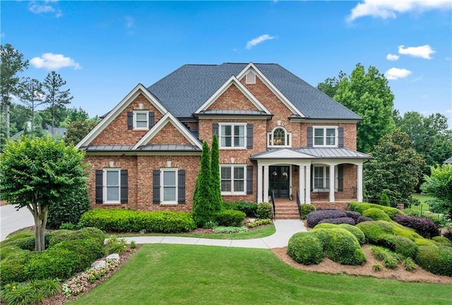 7025 Windsor Hill Psge, Suwanee, GA 30024 - view of front of home featuring a standing seam roof, brick siding, a front lawn, covered porch, and a metal roof
