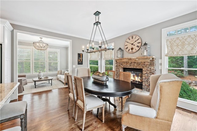 7025 Windsor Hill Psge, Suwanee, GA 30024 - dining space with a chandelier, a stone fireplace, plenty of natural light, wood finished floors, and crown molding