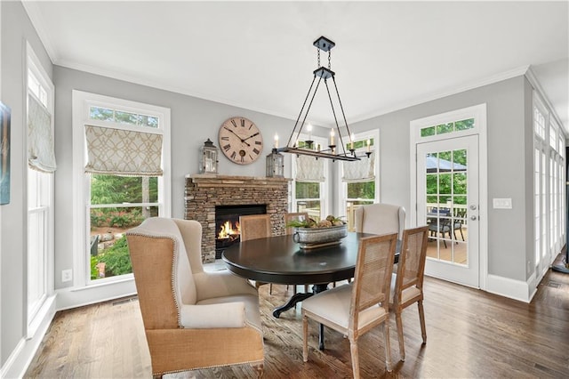 7025 Windsor Hill Psge, Suwanee, GA 30024 - dining room featuring crown molding, dark wood-type flooring, a stone fireplace, and a chandelier