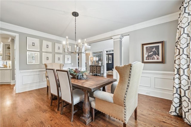 7025 Windsor Hill Psge, Suwanee, GA 30024 - dining area featuring a chandelier, wood finished floors, ornamental molding, a decorative wall, and wainscoting