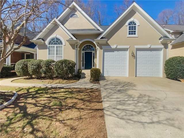 view of front of home with concrete driveway, an attached garage, and stucco siding