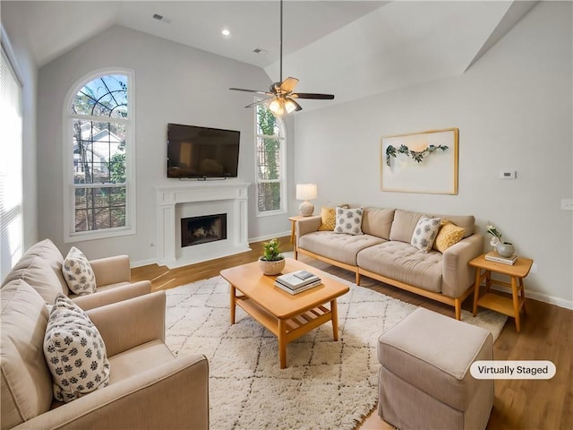 living room with baseboards, visible vents, lofted ceiling, wood finished floors, and a fireplace