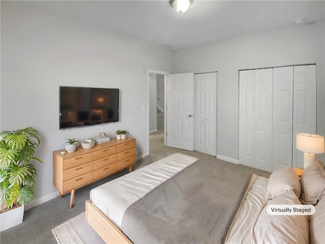 bedroom with carpet flooring, baseboards, and two closets