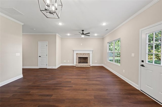 unfurnished living room with dark wood-type flooring, crown molding, a brick fireplace, and plenty of natural light