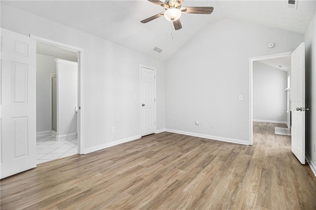 unfurnished bedroom with light wood-type flooring, baseboards, and vaulted ceiling