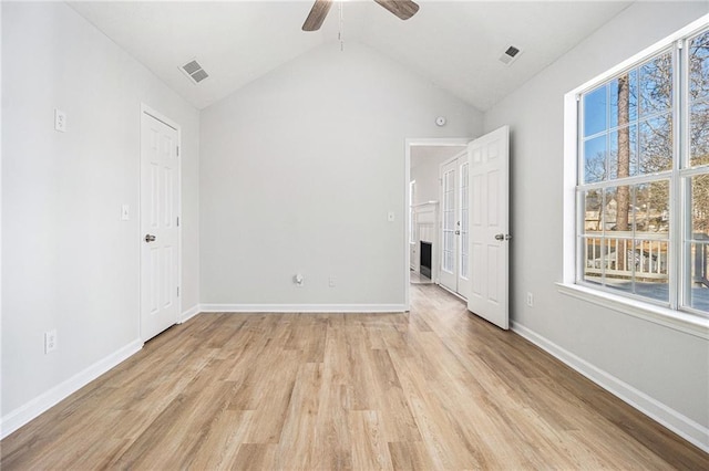 unfurnished bedroom with light wood-type flooring, visible vents, lofted ceiling, and baseboards