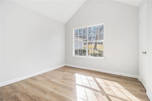 empty room featuring lofted ceiling, light wood-style floors, and baseboards