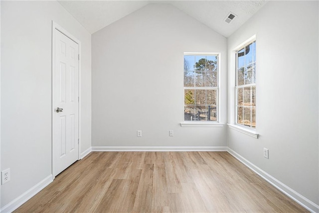 interior space featuring lofted ceiling, light wood-style floors, multiple windows, and visible vents