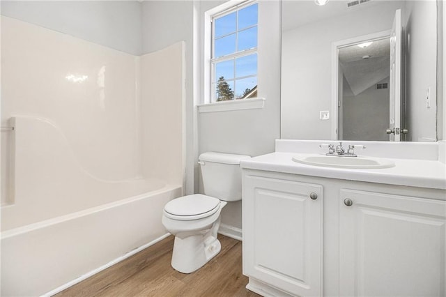 bathroom with toilet, wood finished floors, visible vents, vanity, and shower / bathing tub combination