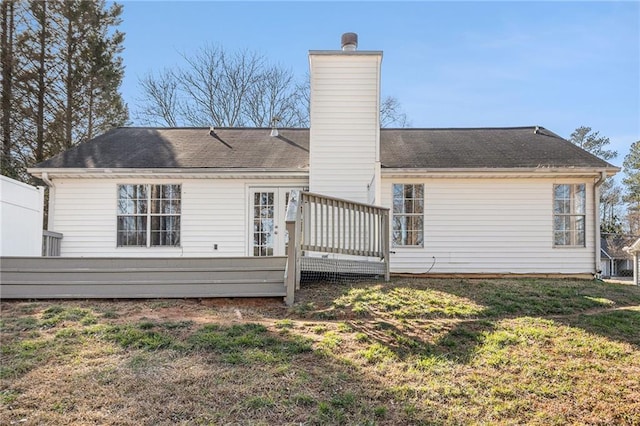 back of property with a deck, a yard, and a chimney