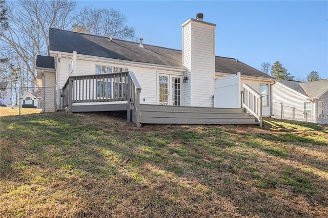 rear view of property featuring a lawn, a chimney, a wooden deck, and fence