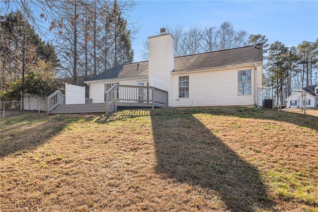 rear view of property with a chimney, fence, a deck, and a yard