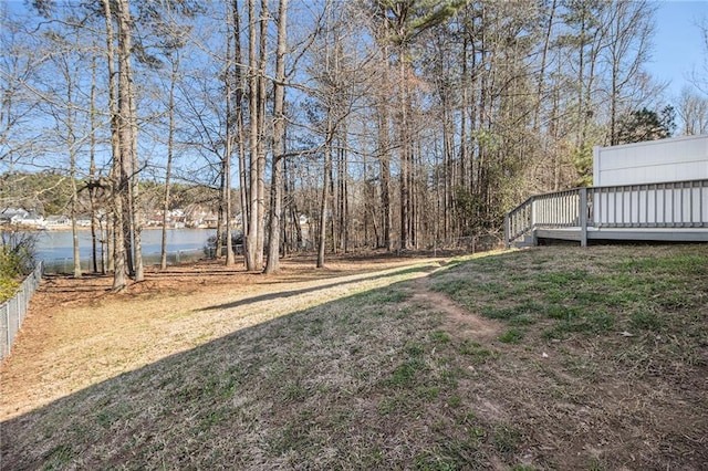 view of yard featuring a deck with water view and fence