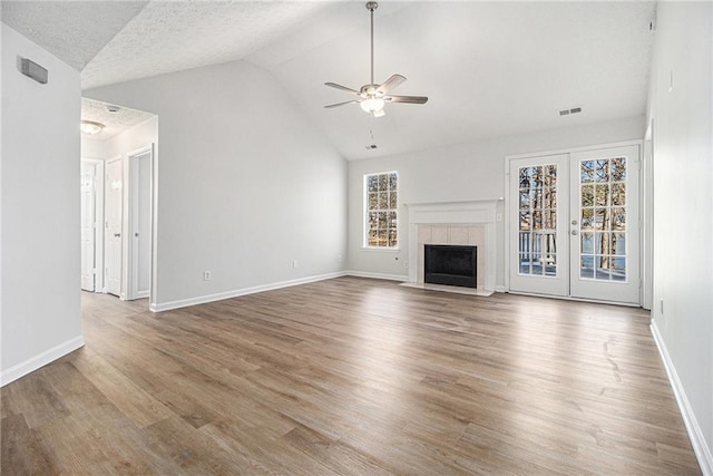 unfurnished living room featuring baseboards, visible vents, a tiled fireplace, ceiling fan, and wood finished floors