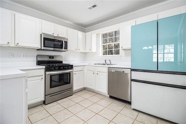 kitchen with a sink, appliances with stainless steel finishes, white cabinets, and light countertops