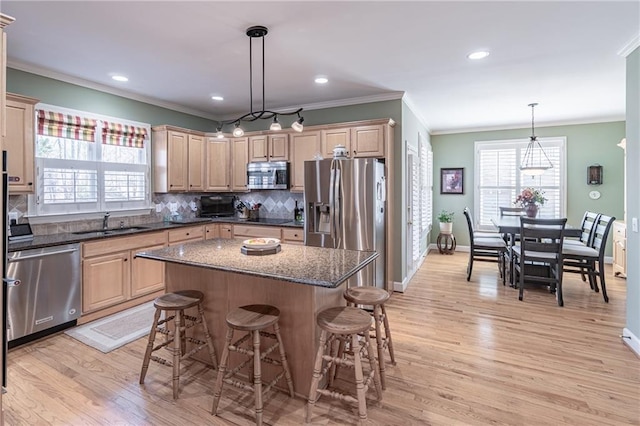 kitchen featuring backsplash, a breakfast bar area, a wealth of natural light, stainless steel appliances, and a sink