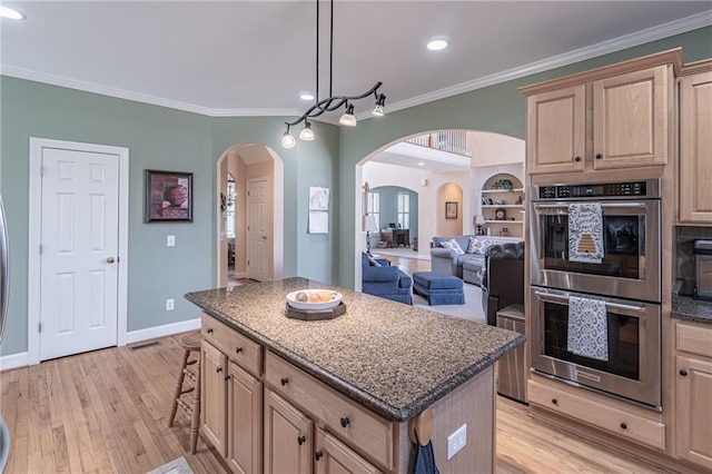 kitchen featuring a kitchen island, ornamental molding, light brown cabinetry, light wood-style floors, and double oven