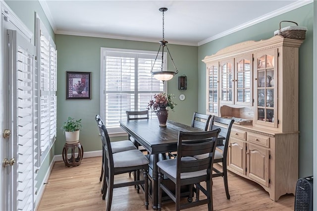 dining area with baseboards, light wood-style flooring, and crown molding