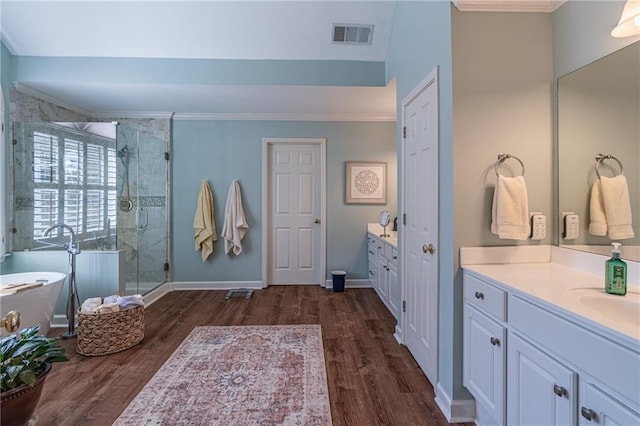 full bath featuring a shower stall, two vanities, wood finished floors, and visible vents