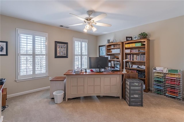 office space featuring baseboards, light colored carpet, visible vents, and ceiling fan