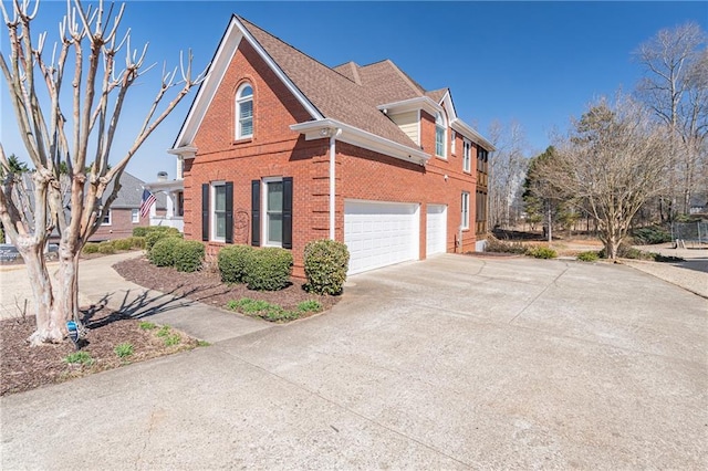 view of side of property with an attached garage, brick siding, driveway, and roof with shingles