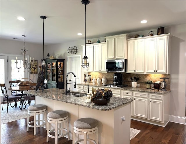 4745 Belcrest Way, Cumming, GA 30040 - kitchen featuring appliances with stainless steel finishes, dark wood-style flooring, backsplash, light stone countertops, and decorative light fixtures