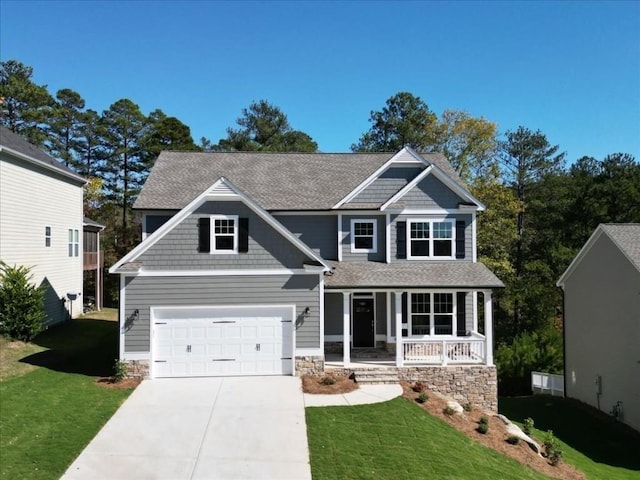 craftsman inspired home featuring a front yard, driveway, a porch, stone siding, and a garage