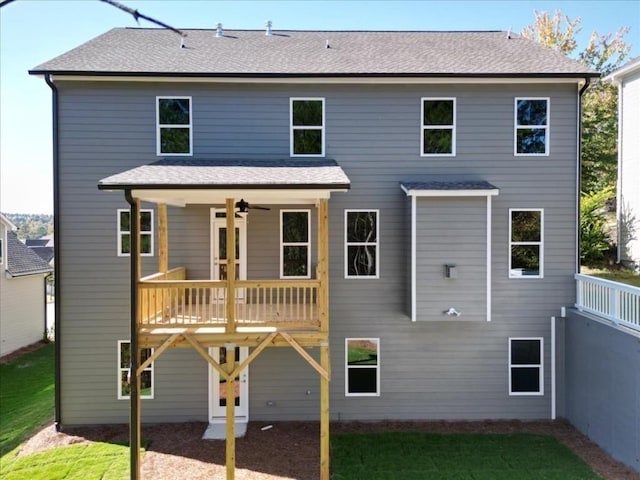 rear view of property with a lawn, a shingled roof, a deck, and ceiling fan