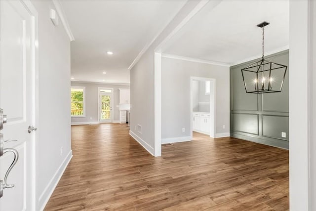 foyer featuring a chandelier, crown molding, baseboards, and wood finished floors