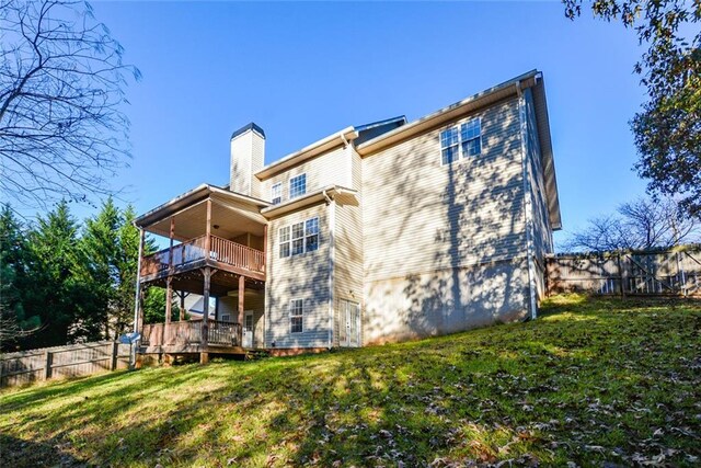 back of house featuring a lawn and a wooden deck