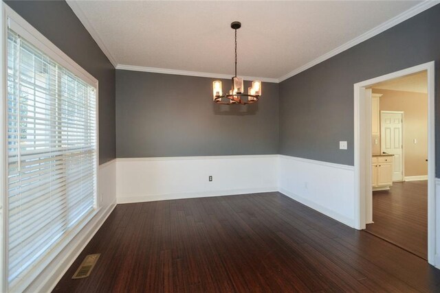 spare room with crown molding, dark hardwood / wood-style flooring, and a notable chandelier