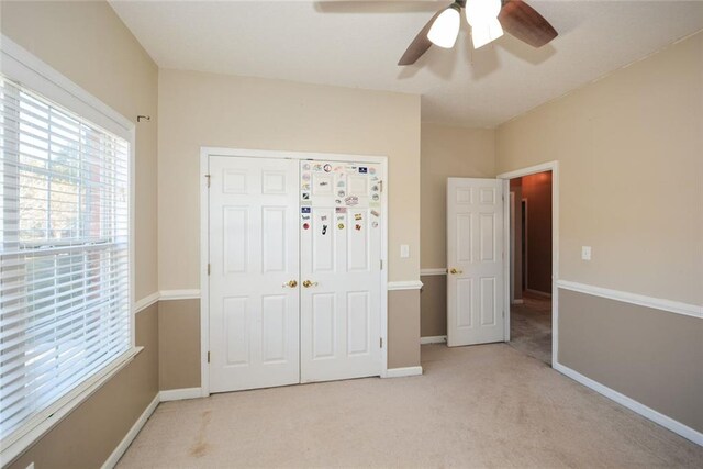 unfurnished bedroom featuring a closet, light colored carpet, and ceiling fan