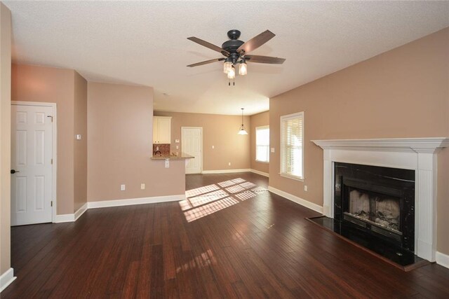 unfurnished living room featuring dark hardwood / wood-style floors, ceiling fan, and a textured ceiling