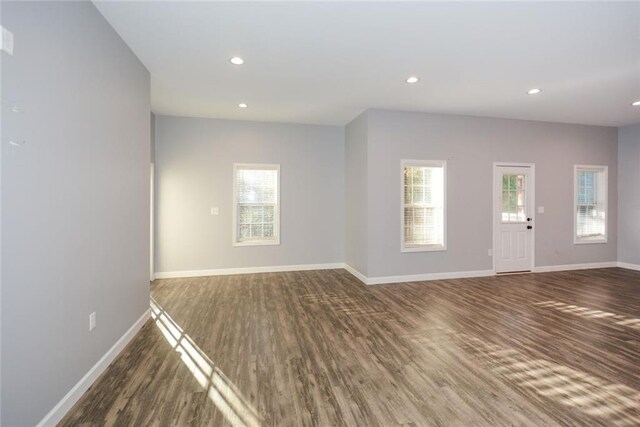 unfurnished living room featuring dark hardwood / wood-style flooring and a healthy amount of sunlight