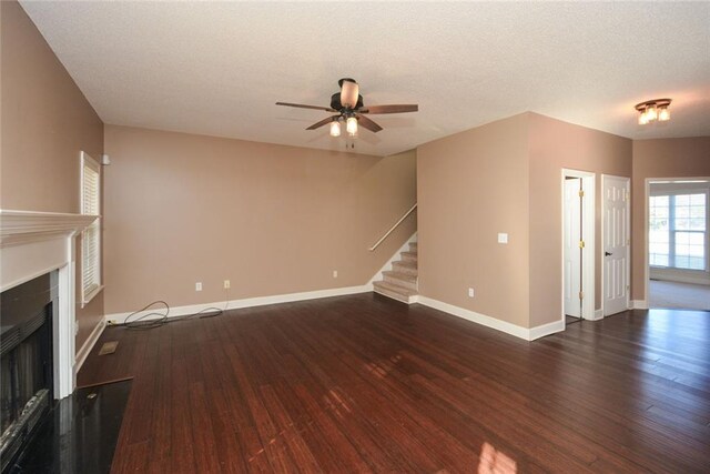 unfurnished living room featuring a textured ceiling, ceiling fan, and dark wood-type flooring