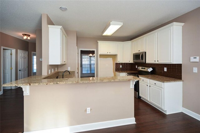 kitchen with white cabinets, appliances with stainless steel finishes, dark hardwood / wood-style flooring, and light stone counters