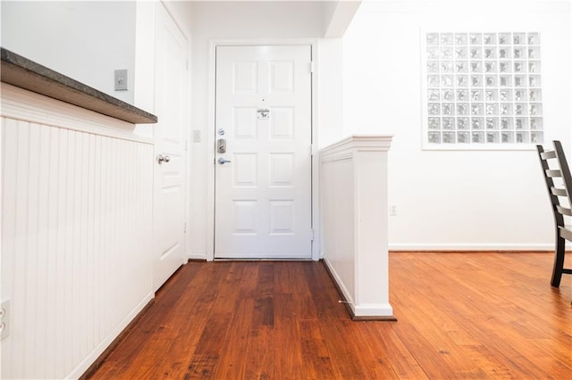 doorway with baseboards and dark wood-style flooring