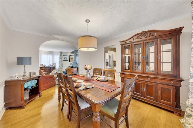 dining space featuring a textured ceiling, light wood-type flooring, and ornamental molding