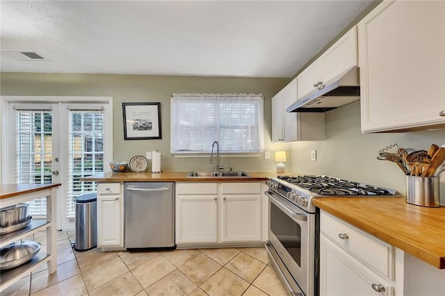 kitchen with butcher block countertops, white cabinets, sink, and appliances with stainless steel finishes