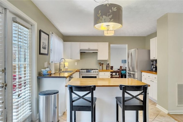 kitchen with white cabinetry, sink, stainless steel appliances, wood counters, and decorative light fixtures