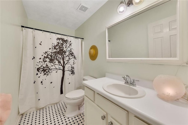 bathroom featuring tile patterned flooring, vanity, a textured ceiling, and toilet