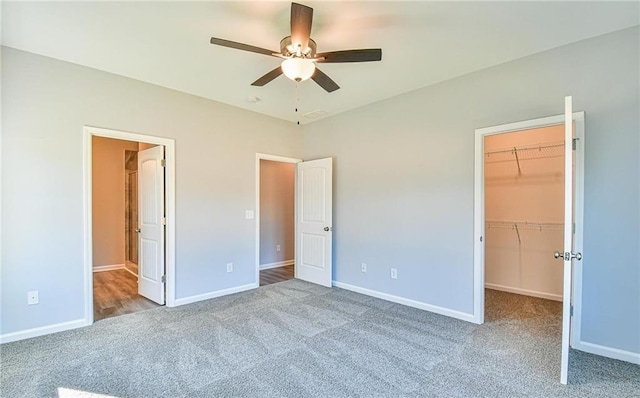 unfurnished bedroom featuring carpet flooring, baseboards, a spacious closet, and a closet