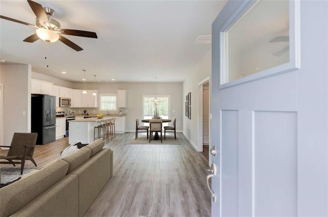 living room with light wood-style floors, baseboards, ceiling fan, and recessed lighting