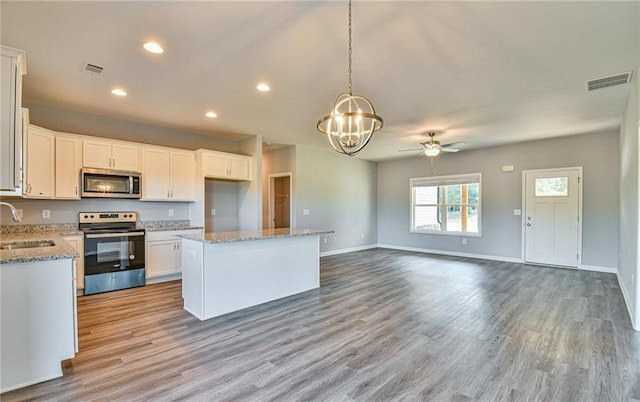 kitchen featuring stainless steel appliances, visible vents, a sink, and ceiling fan with notable chandelier