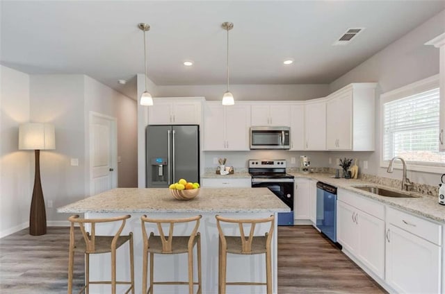 kitchen with a sink, stainless steel appliances, white cabinetry, and visible vents