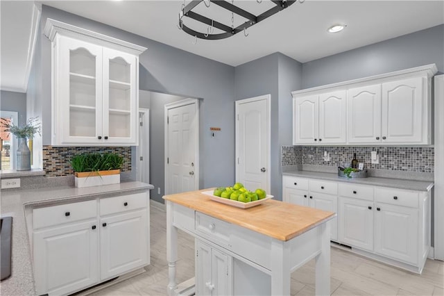 kitchen with decorative backsplash, white cabinets, glass insert cabinets, and wooden counters